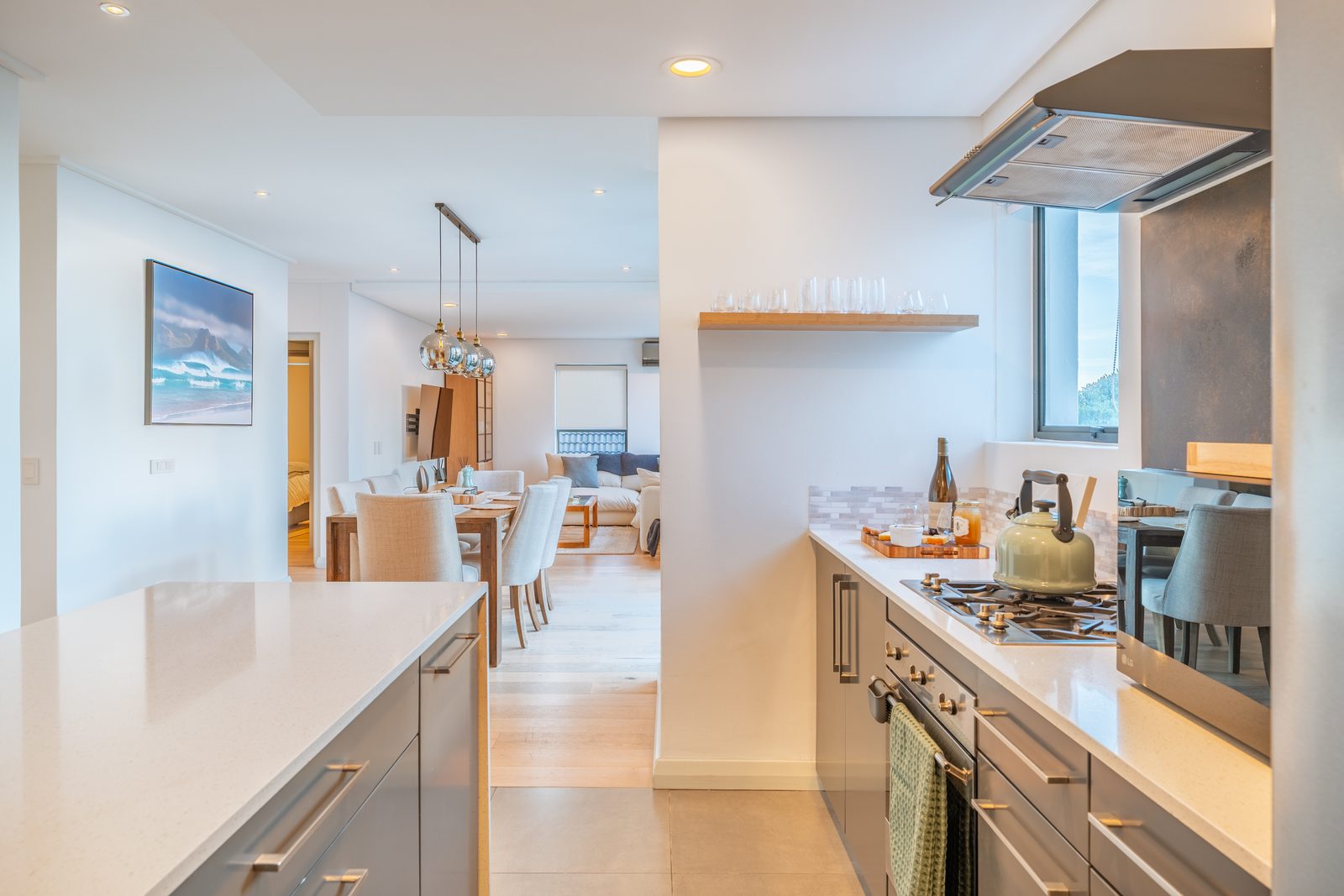 Kitchen with light stone worktops, hob and oven, looking through to the dining area