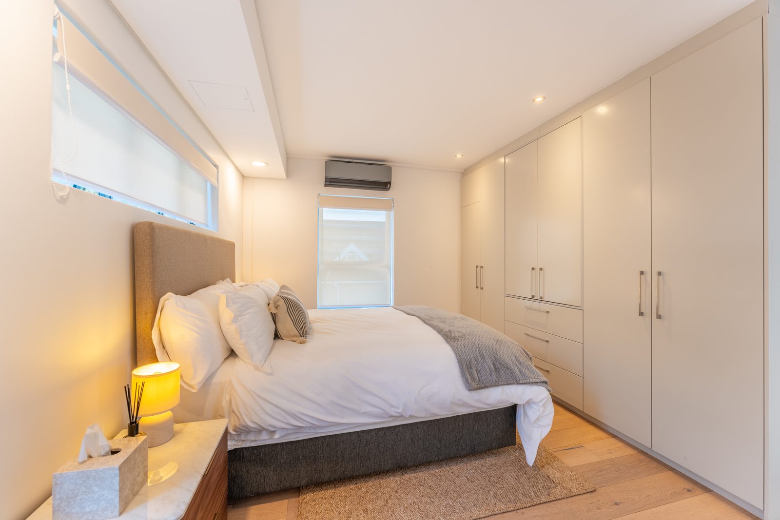 Master bedroom with an upholstered headboard, white linen and built-in wardrobes