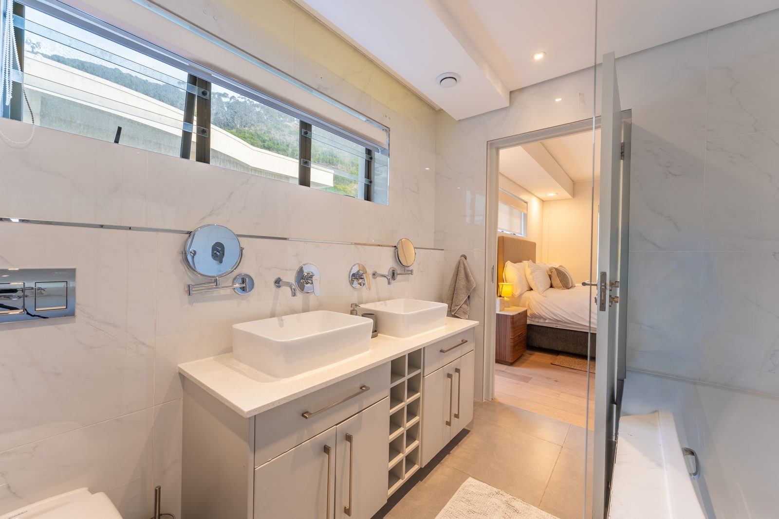 En-suite bathroom with double basins, marble-look tiles and a bath with shower