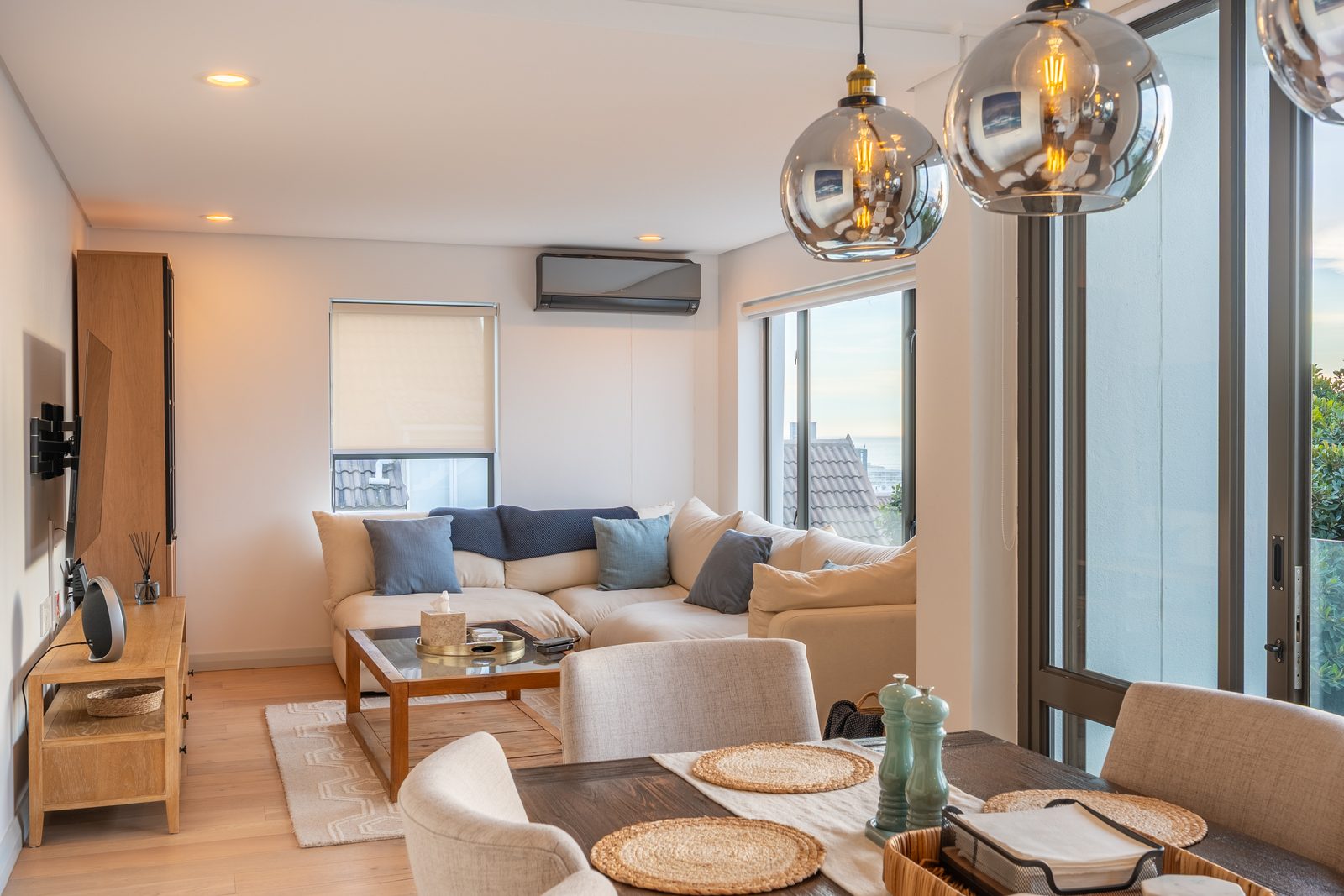 Living area seen across the dining table, with floor-to-ceiling windows
