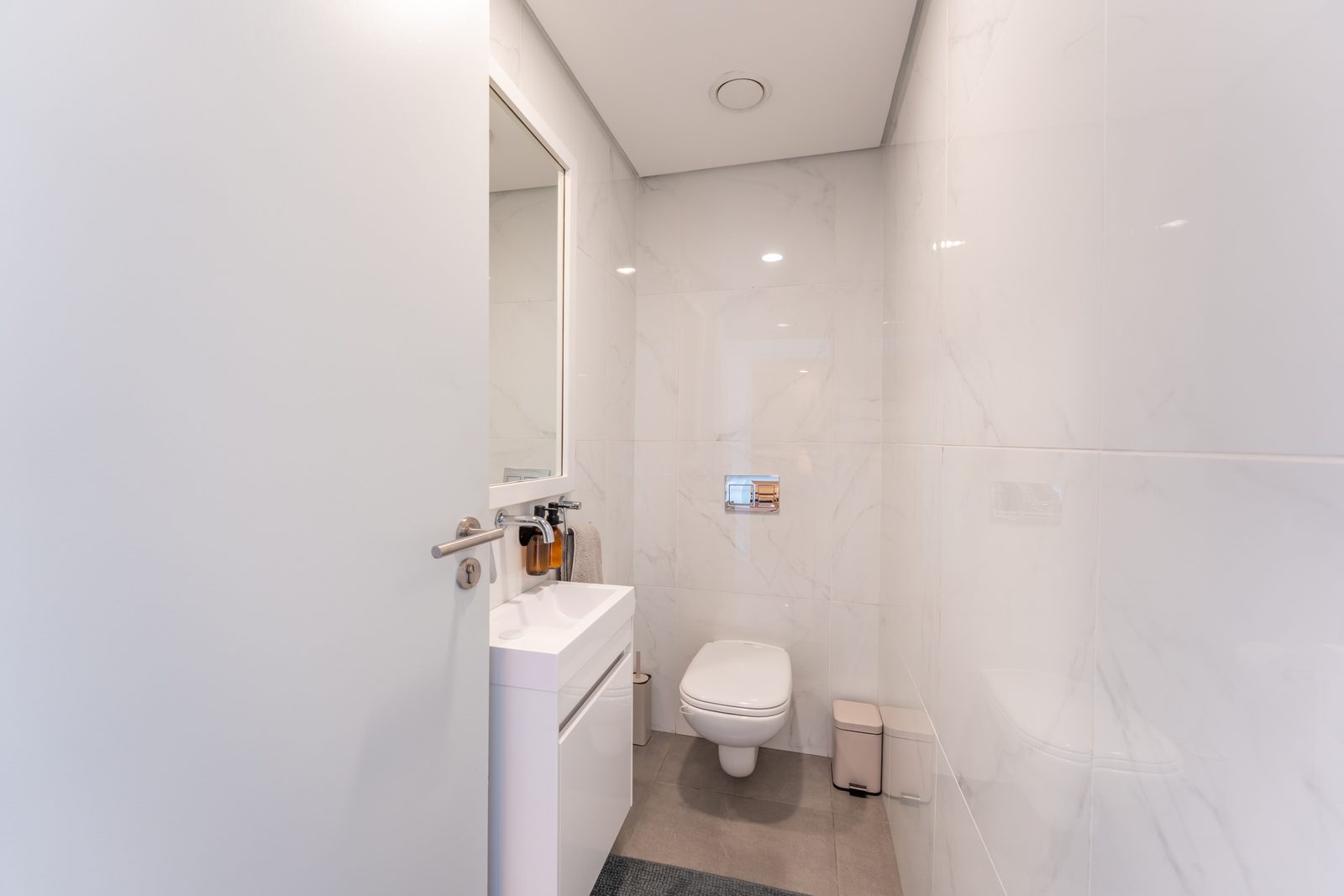 Guest loo with marble-look tiles and a wall-hung basin